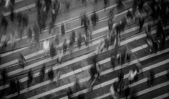 Black and white long exposure photo of a crowd walking across a street