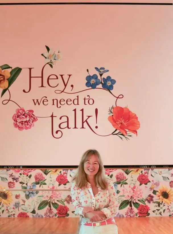 woman posing in front of a sign that says "Hey, we need to talk!"